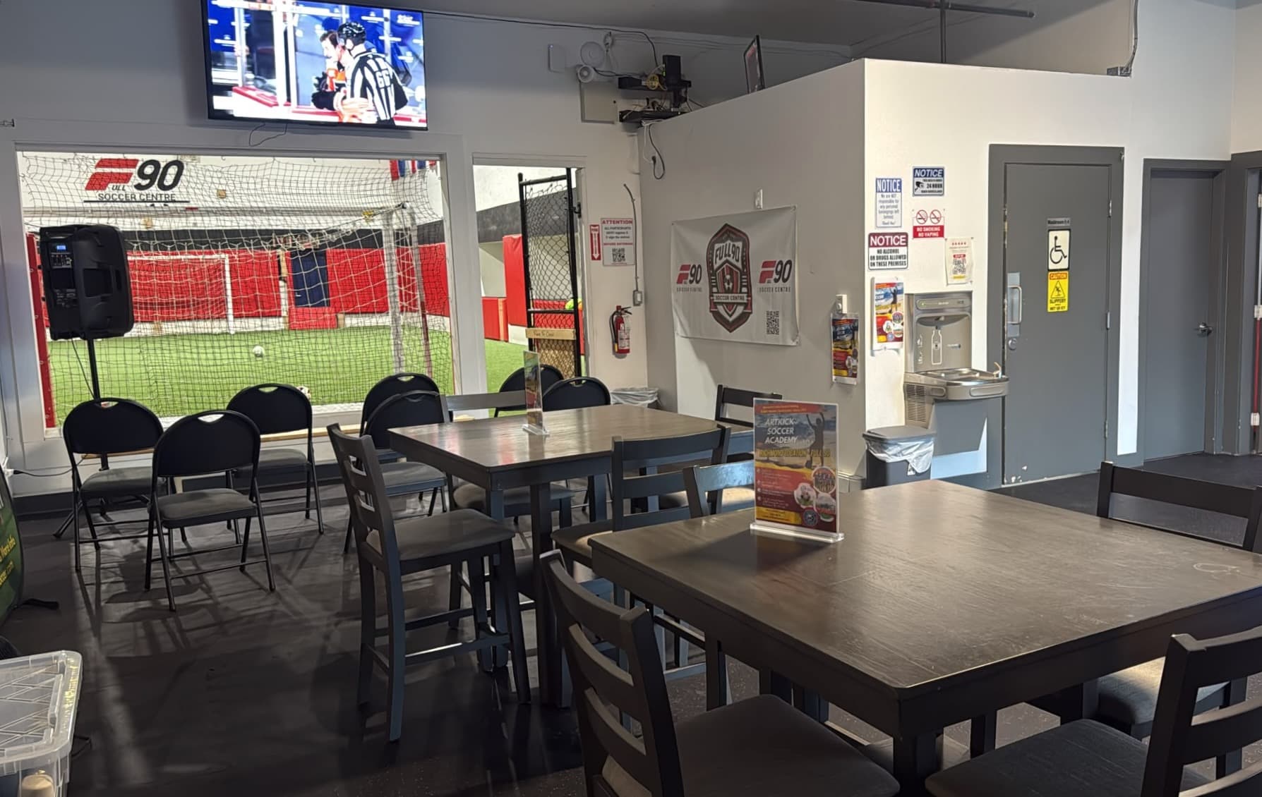 Lobby tables beside a window onto the indoor field